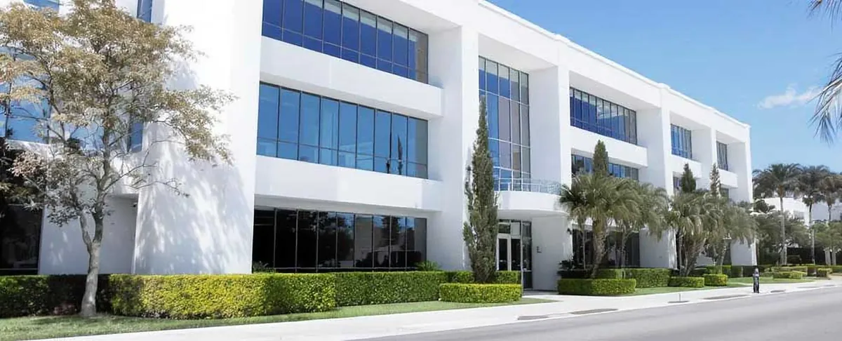 Modern office building with clipped hedges, palms and a manicured lawn