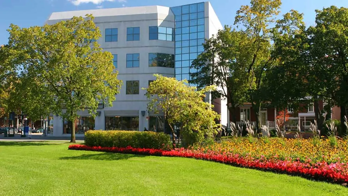 Office building entrance framed by flower beds and lawn