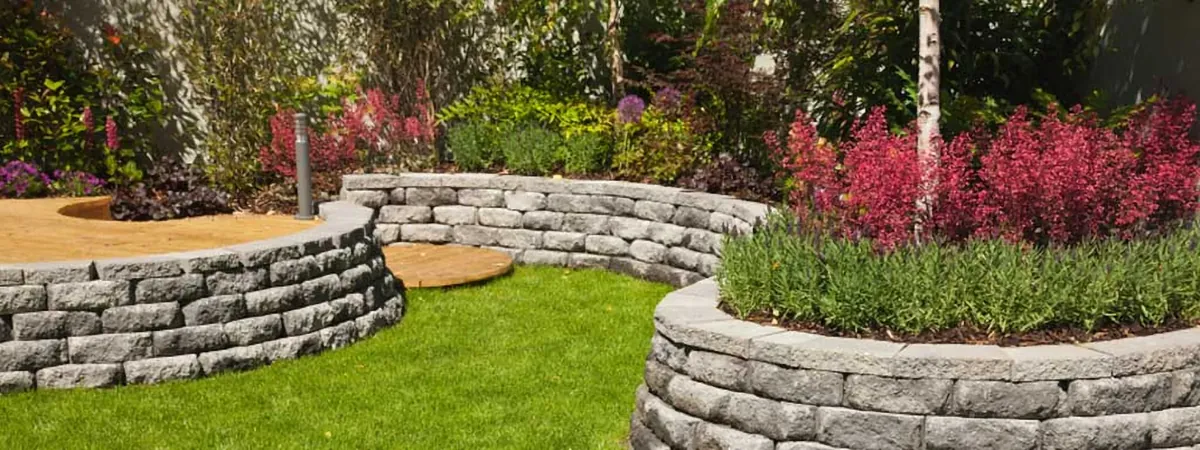 Curved stone retaining walls with planted flower beds